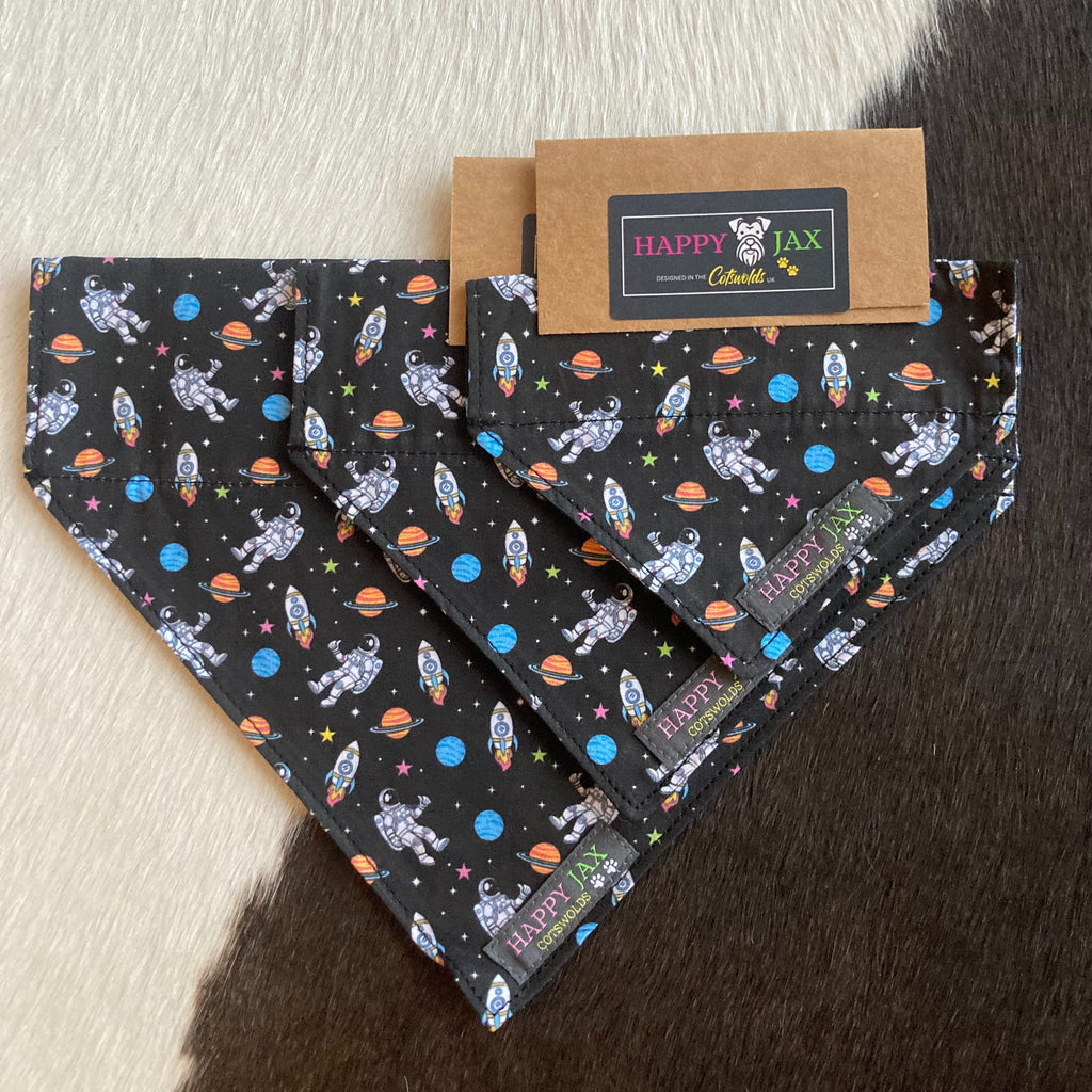 3 different sizes of bandanas with a pattern of astronauts, space ships and colourful planets on a starry black background suitable for our cat and dog collars