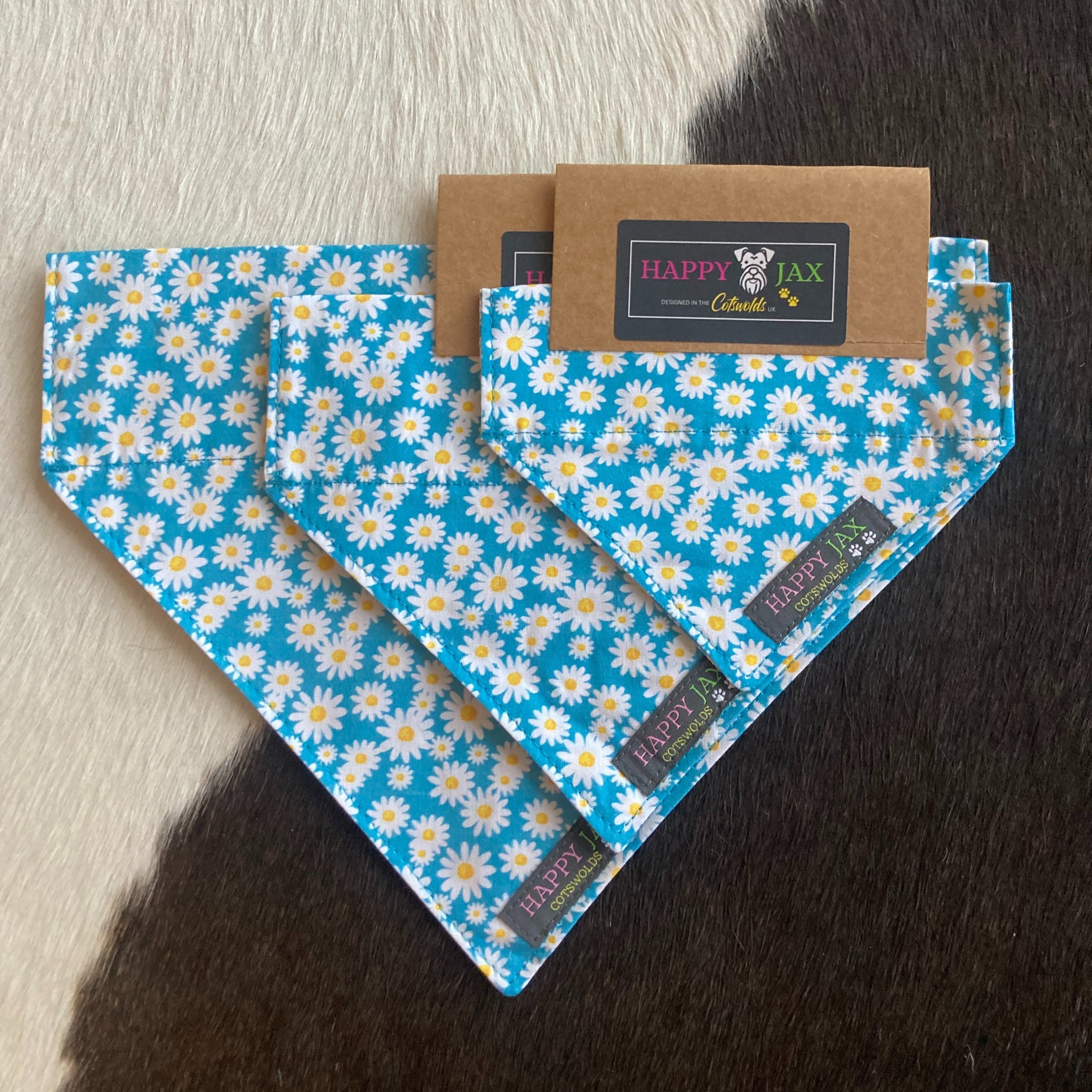 3 different sizes of bandanas which have a daisy pattern on a sky blue background suitable for our matching collars