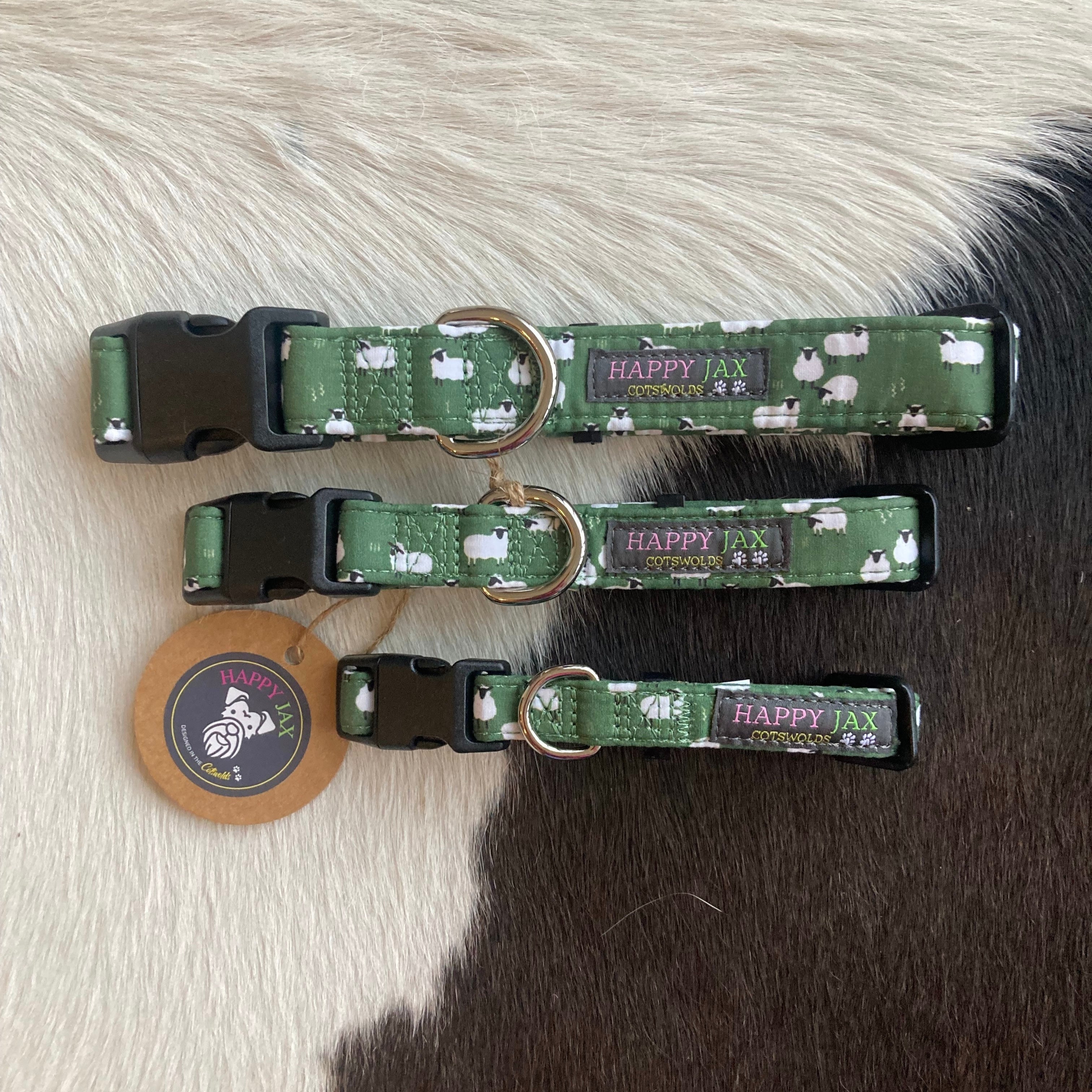 3 animal collars of differing sizes with a pattern of fluffy white sheep on a green grassy background