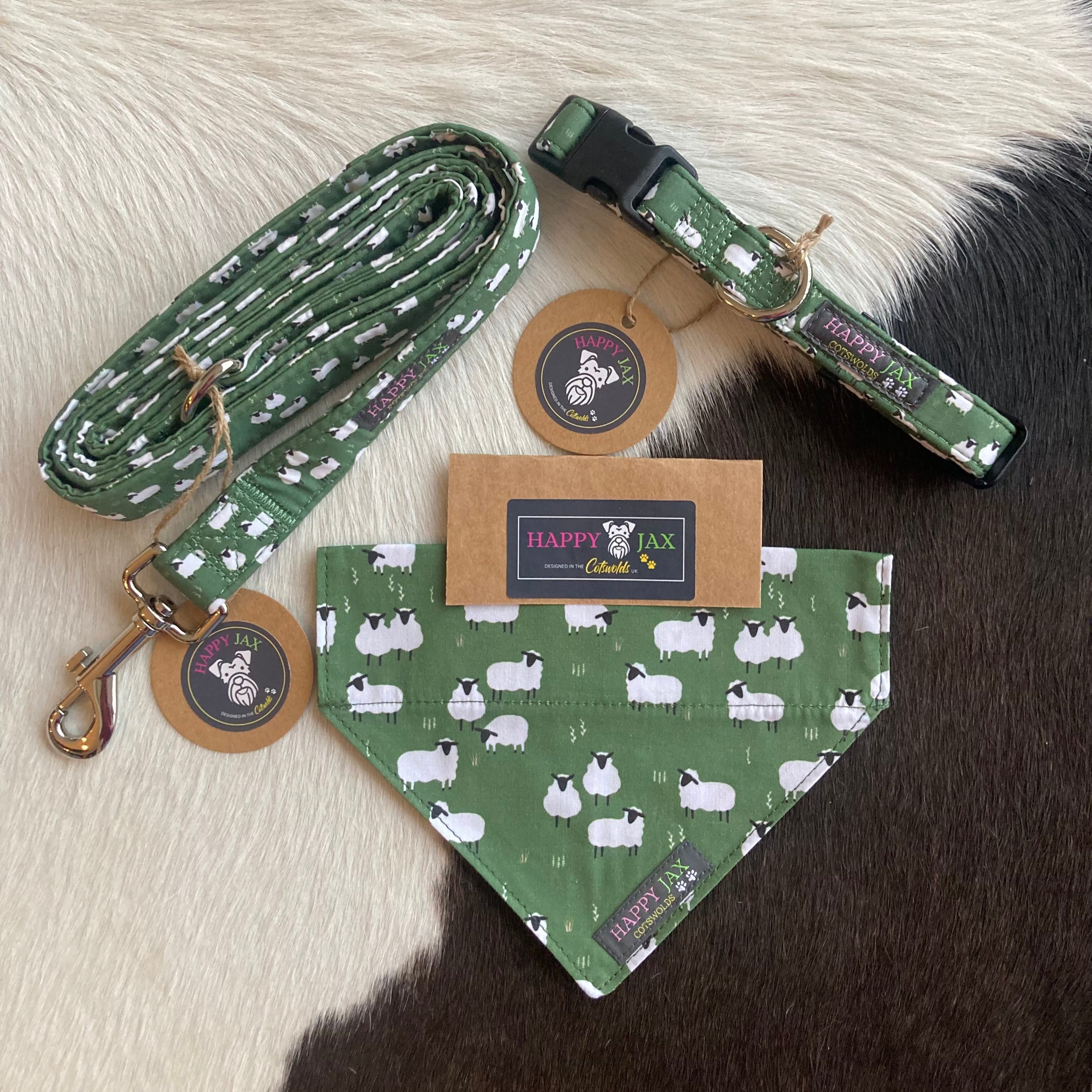 Bundle with an animal collar, bandana and lead in a colourful design of fluffy white sheep grazing on a dark green grass background. Products are suitable for both cats and dogs and available in a range of sizes, made with cotton and designed in the Cotswolds
